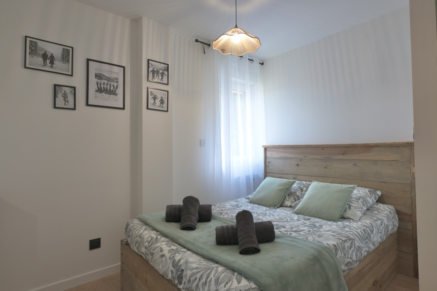Chambre mise en scène par Anne : tête de lit bois, cadres noir et blanc, linge soigné