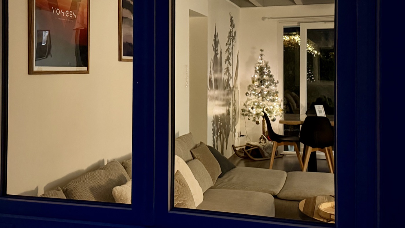 Salon d'un chalet illuminé pour les fêtes, vu depuis l'extérieur
